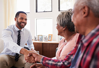 A young businessman shakes hands with an elderly man in a living room